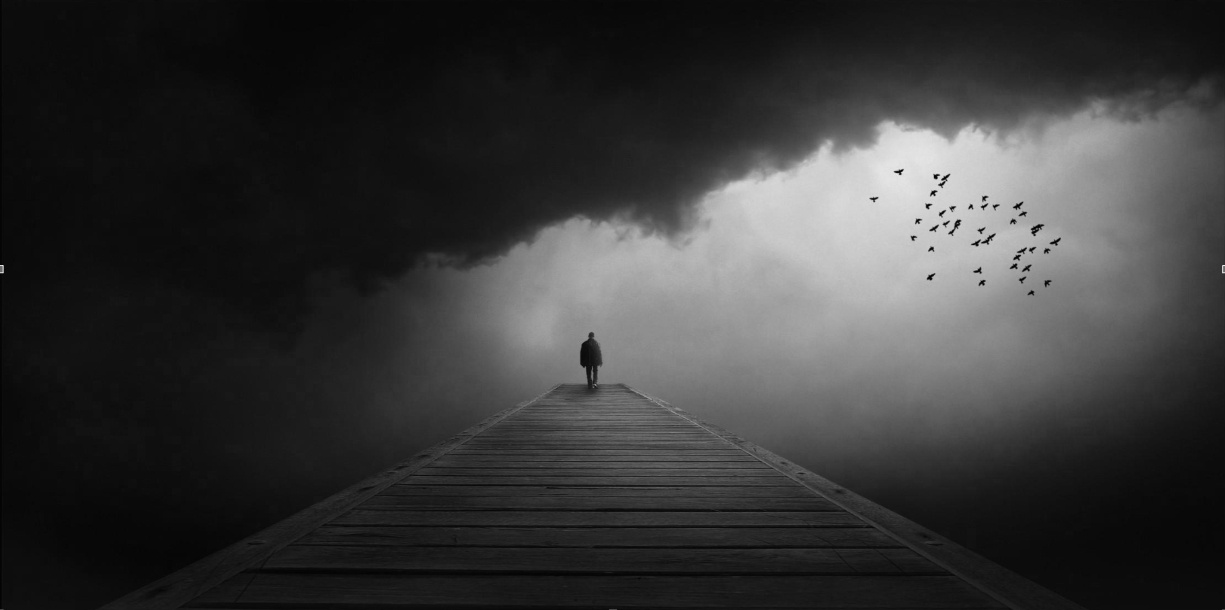 Man standing on a platform in the distance as a storm gathers around him